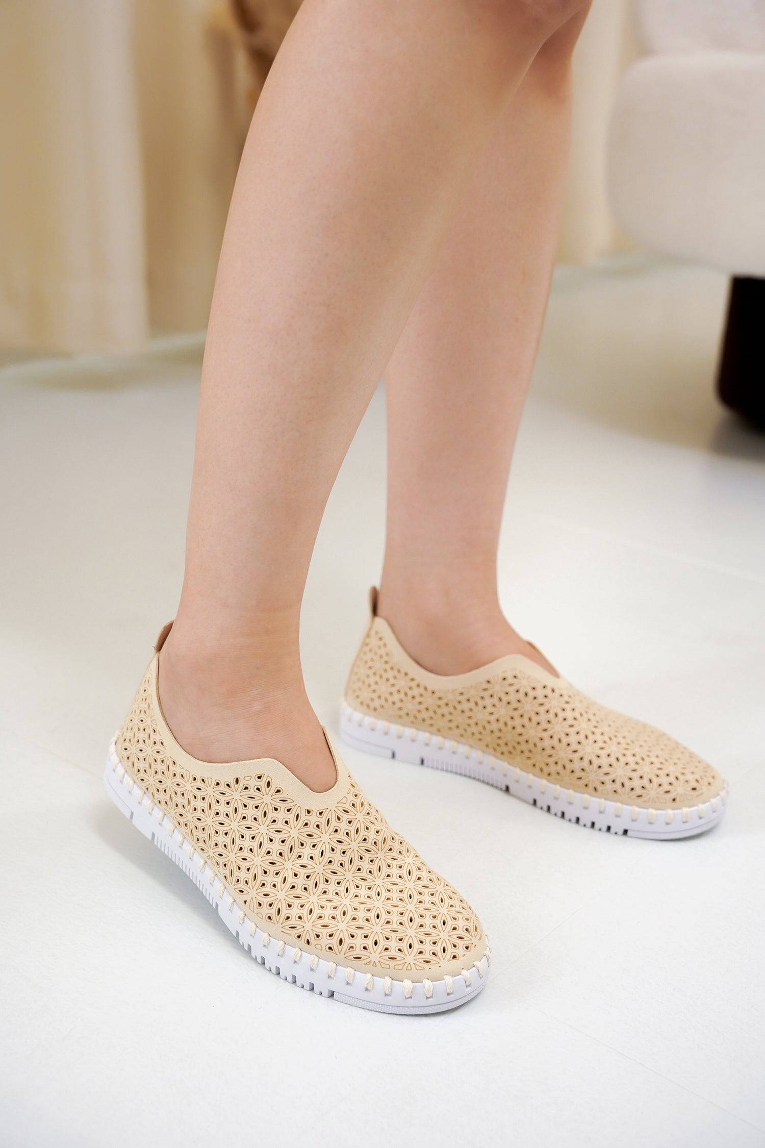 Beige slip-on sneakers for women, floral laser-cut design, white sole, lightweight and breathable.