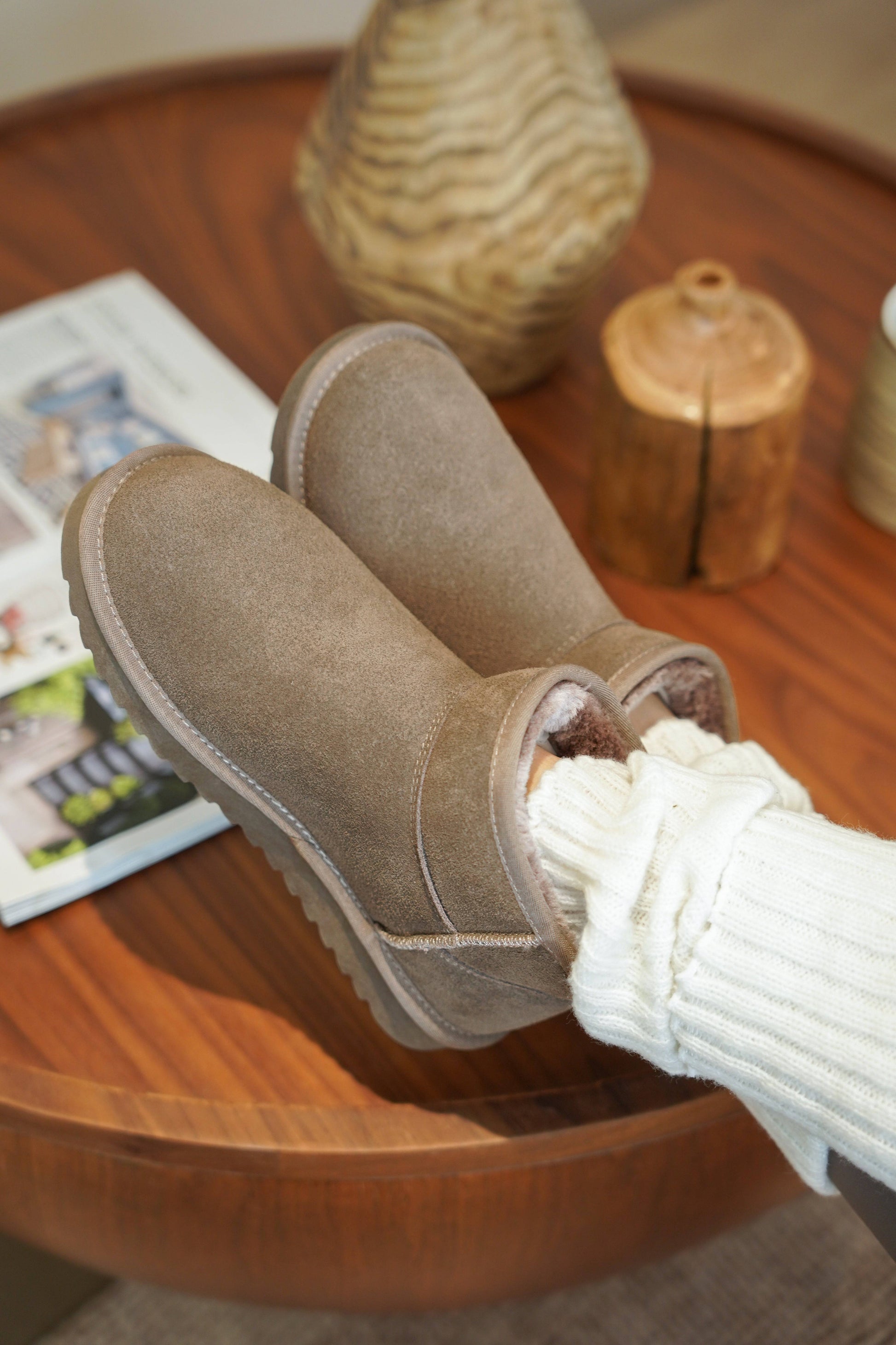 Women's taupe suede Hippy ankle boots, winter-ready with faux fur lining and memory foam insole, resting on a wooden table.