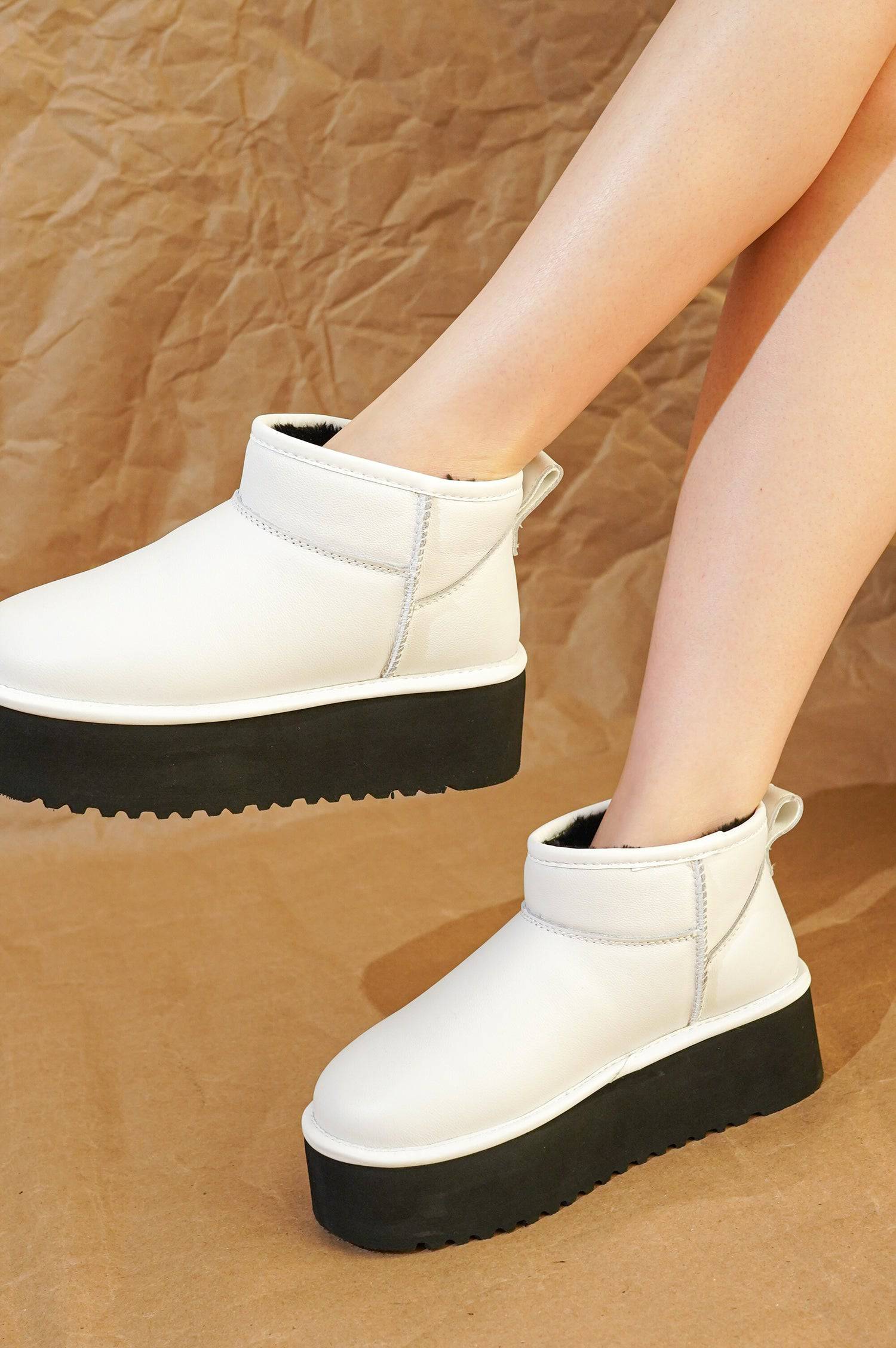 White leather Huggy ankle boots for women with black platform sole, featuring faux fur lining. Lightweight winter boots.