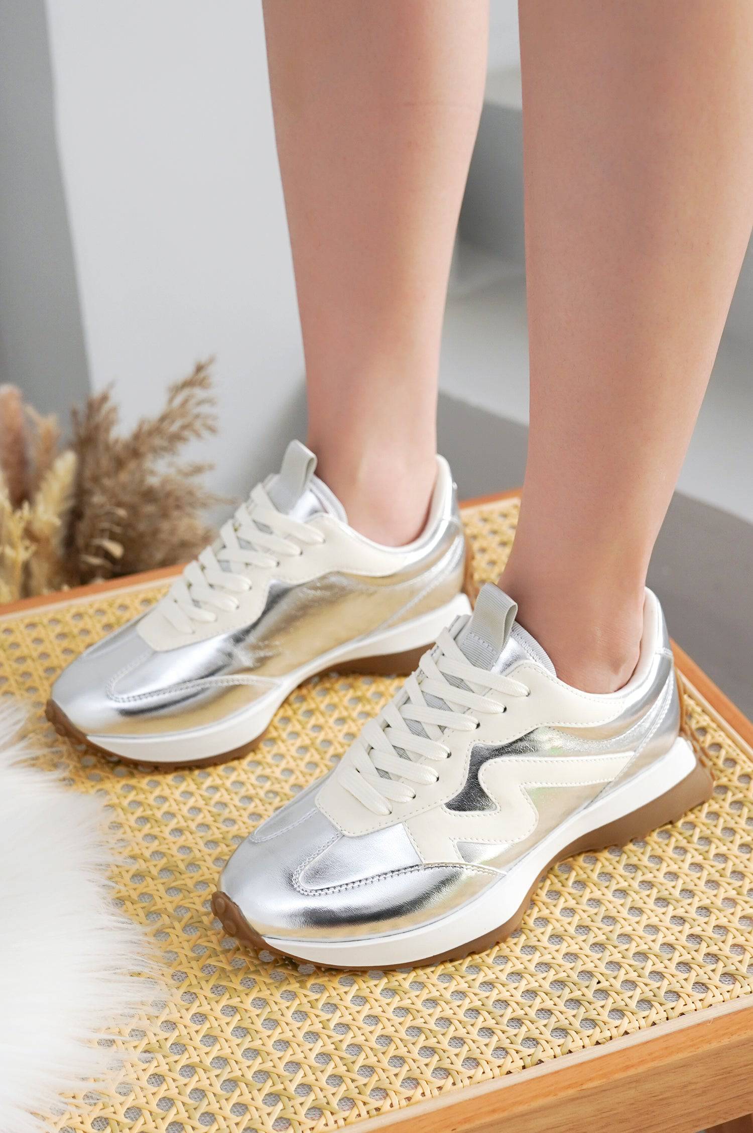 Lecco sneakers for women in silver metallic with white and brown details, on a wicker chair.
