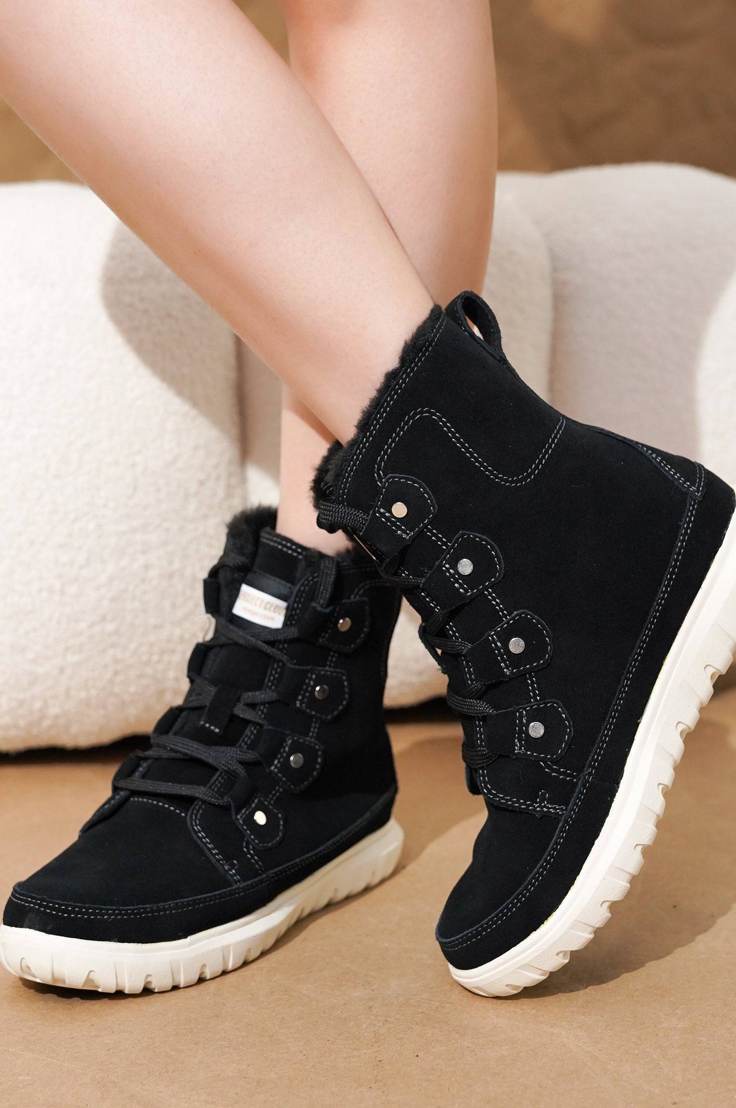 Black suede Leonora snow boots by Project Cloud. Waterproof, white sole, and lace-up design.