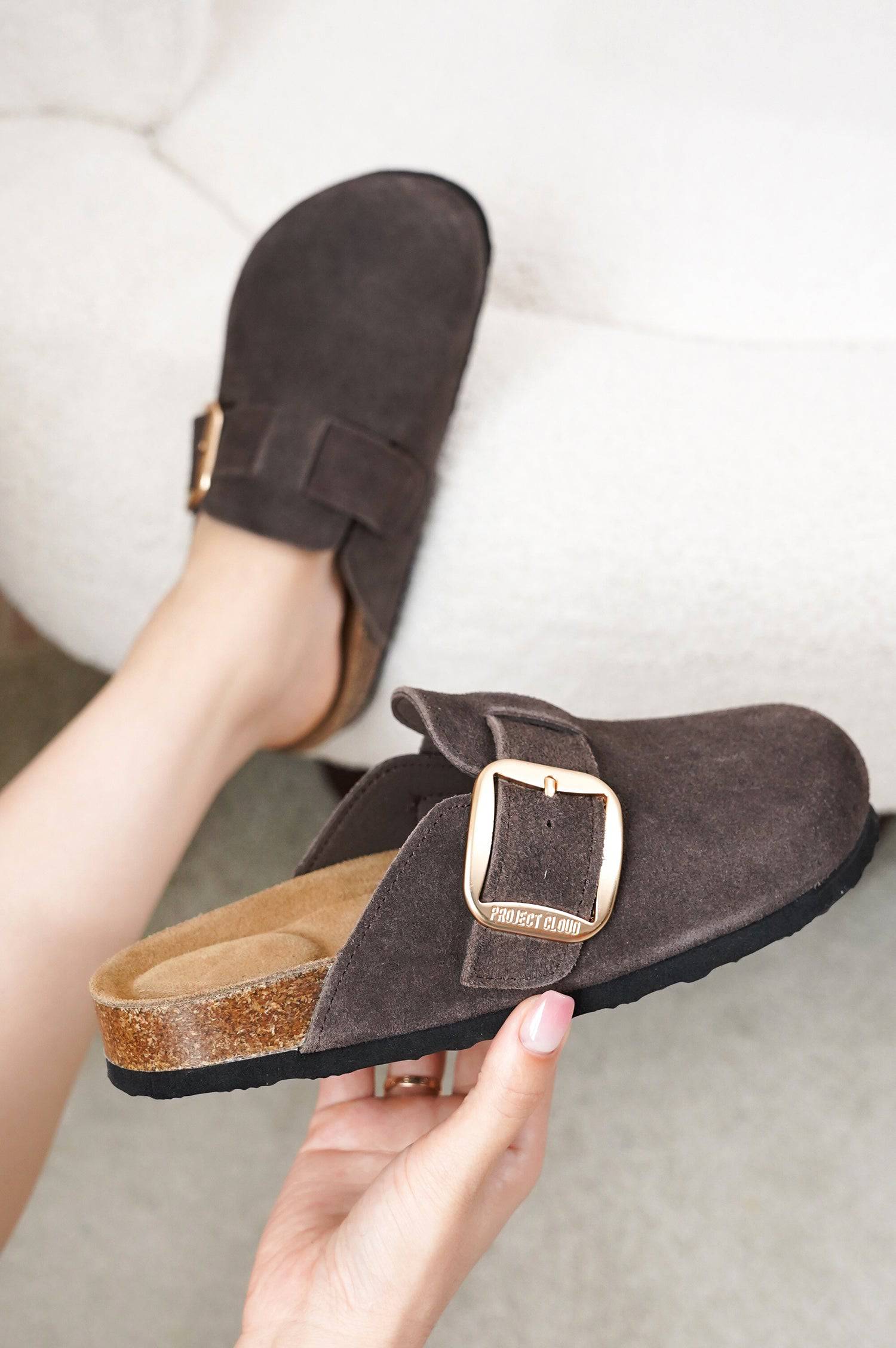 Project Cloud Manchester clogs in brown suede with gold buckle, showing the material and design.