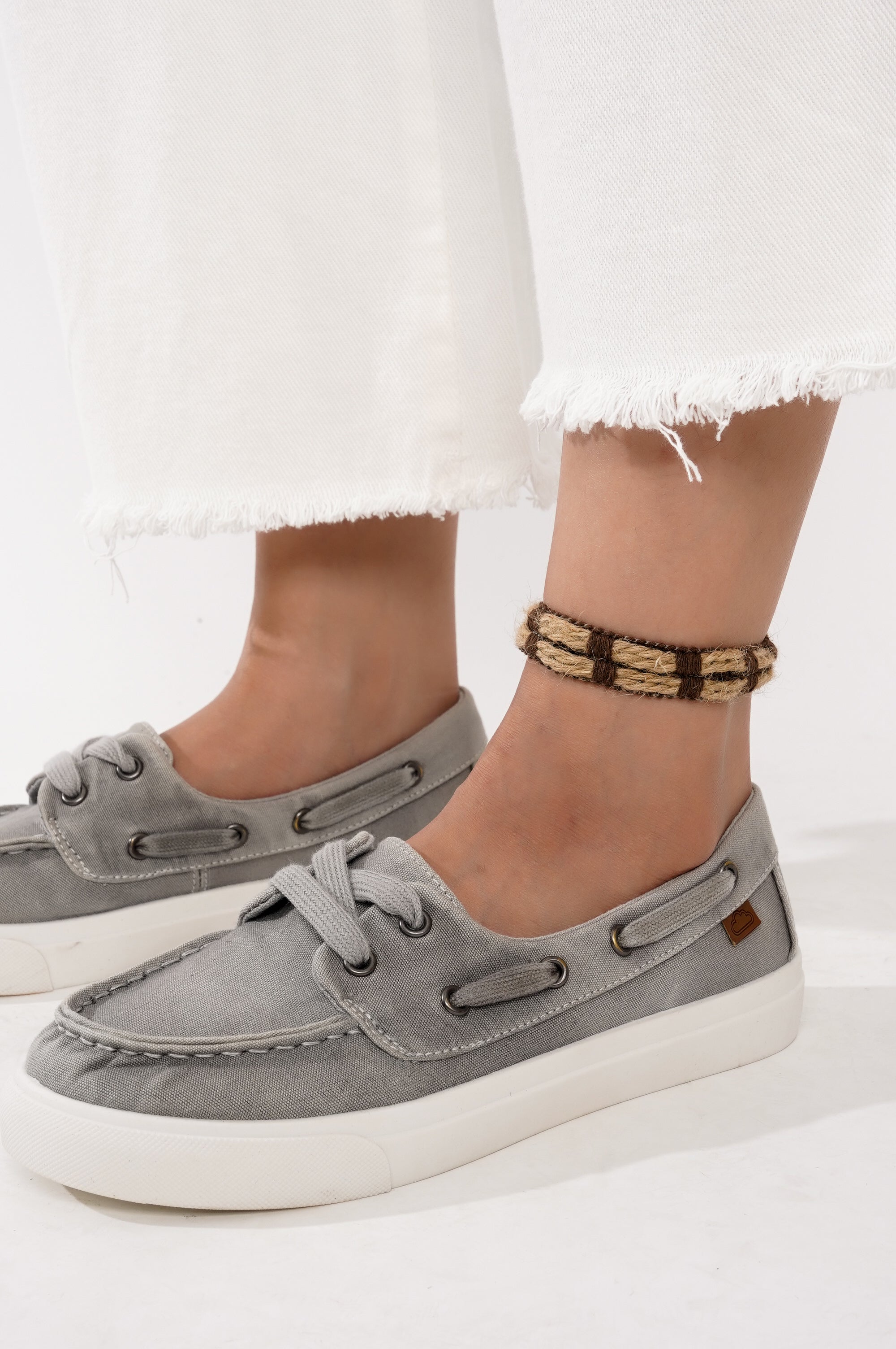 Women's Seasalt gray canvas sneakers with white sole, shown with white jeans and ankle bracelet, Project Cloud brand.